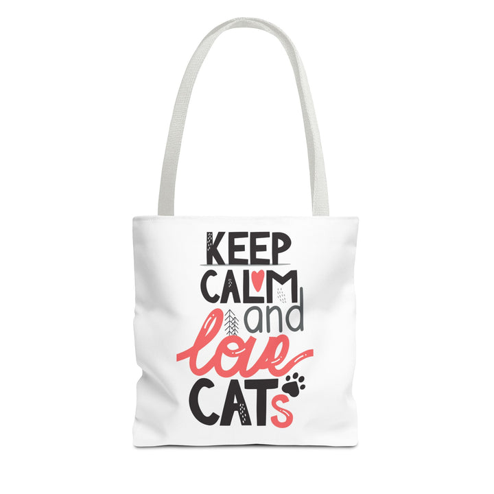 A white canvas tote bag with long shoulder straps, featuring a printed graphic on the front that reads 'KEEP CALM and love CATS' in black and coral pink lettering with small cat-themed accents.