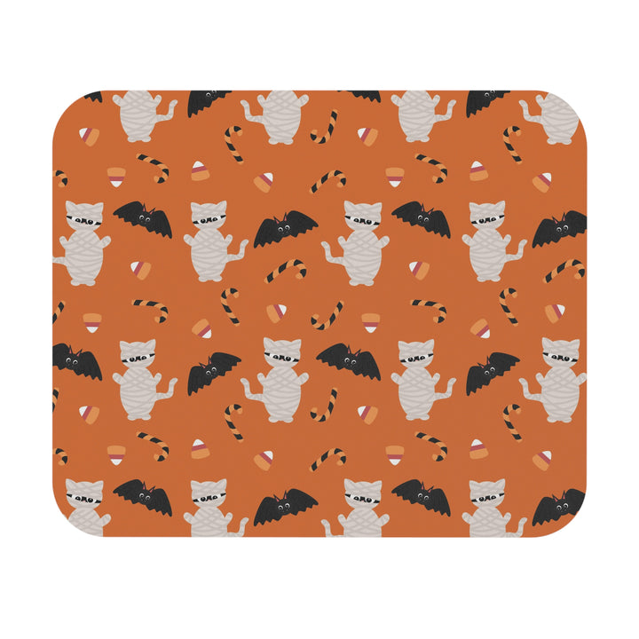 Halloween-themed mouse pad with cats, bats, and candy corn on an orange background