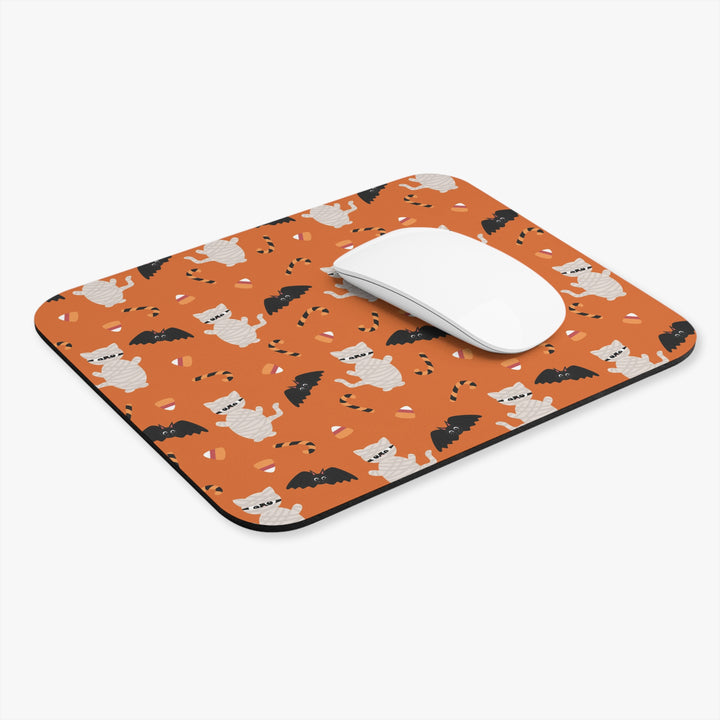 Mouse pad with Halloween-themed design featuring cats and bats on an orange background, with a white mouse on top.