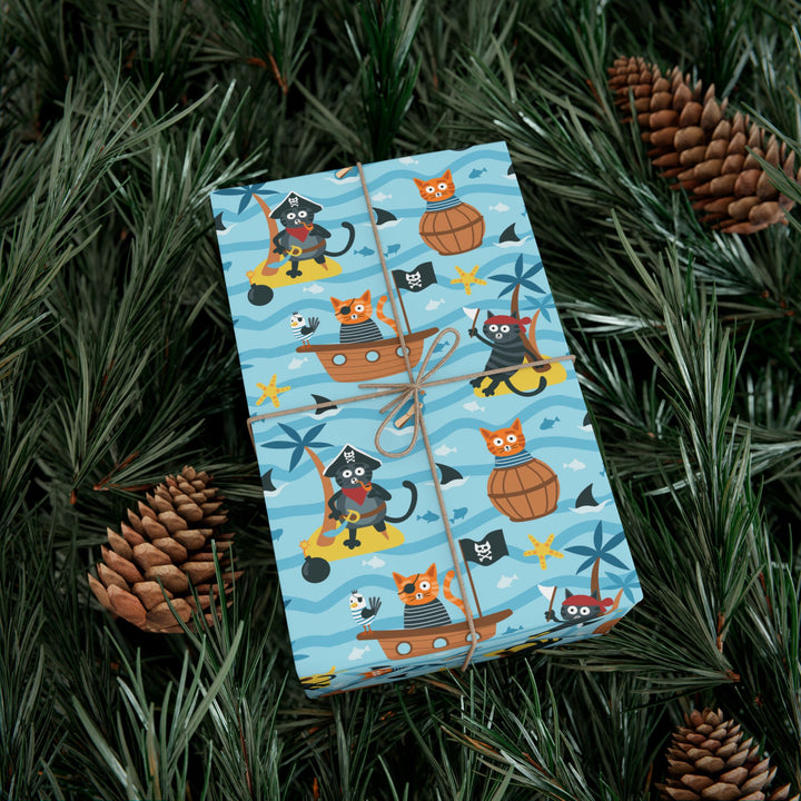 Gift box with cat pirate-themed wrapping paper on a bed of pine needles and pinecones.