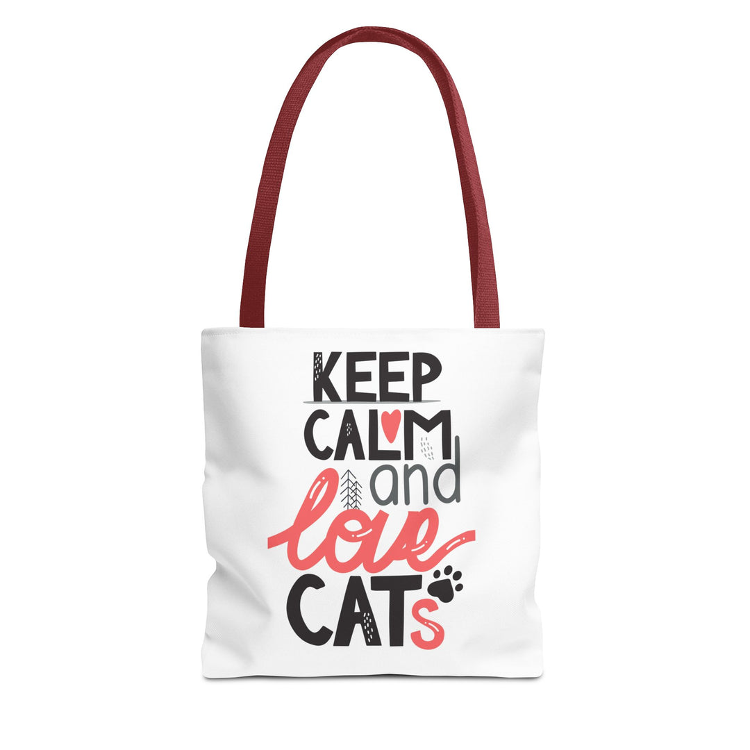 A white canvas tote bag with dark red shoulder straps, featuring the printed text 'KEEP CALM and love CATS' in black and coral pink lettering on the front, set against a plain white background.