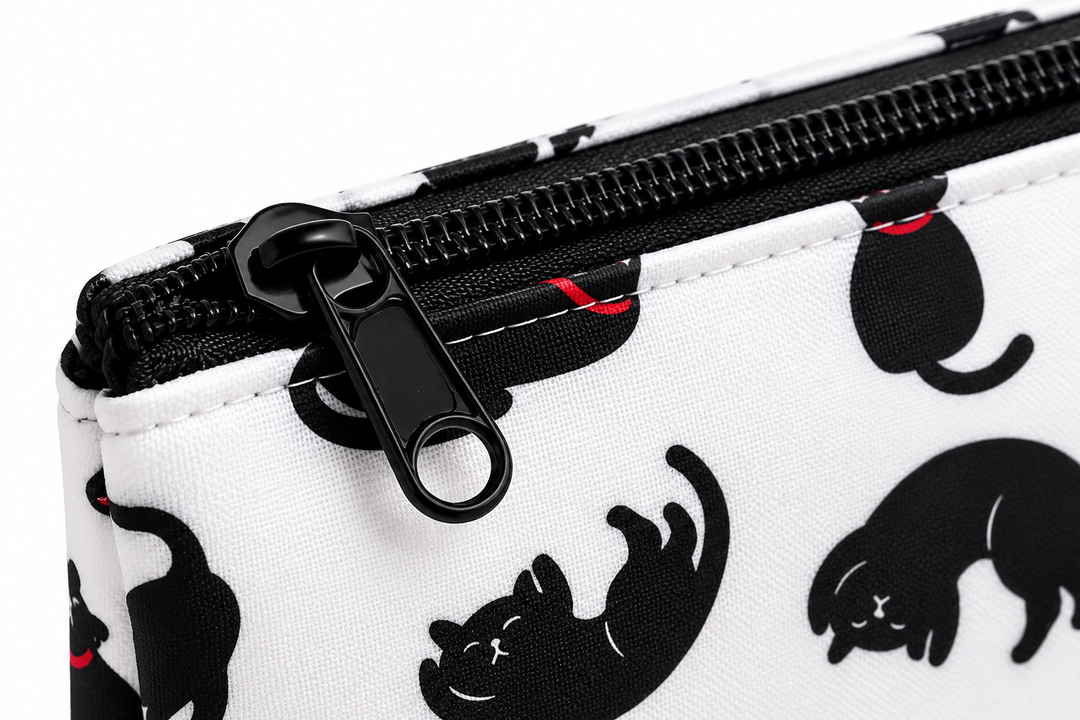 Close-up of a white zipper pouch featuring a black cat silhouette pattern and a black zipper pull, shown on a white background.