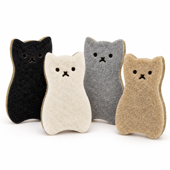 Four cat-shaped kitchen sponges  in black, cream, gray, and tan, arranged in a row on a white background.