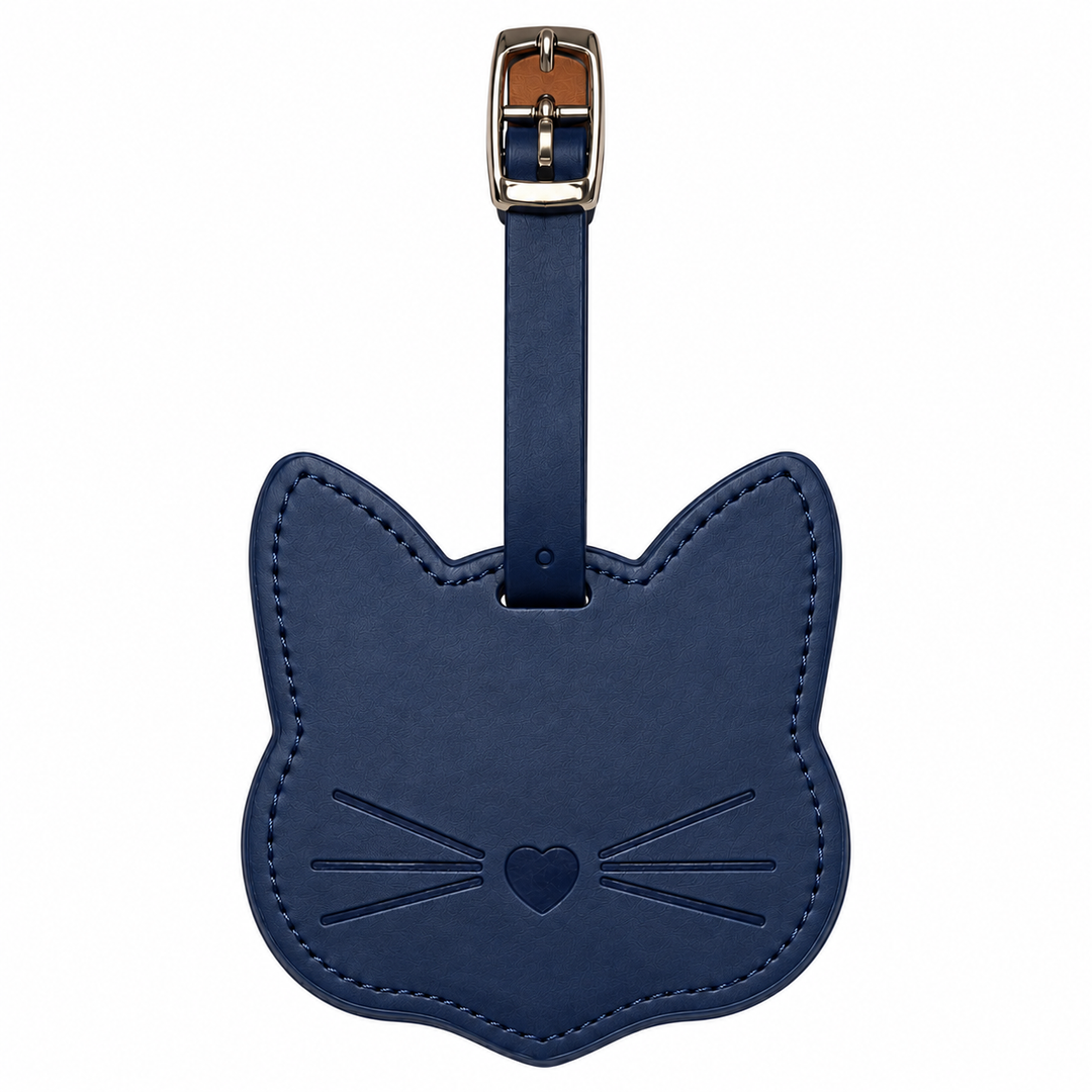 A navy blue leather luggage tag shaped like a cat's head, featuring an embossed face with whiskers and a heart, attached to a matching strap with a silver metal buckle.