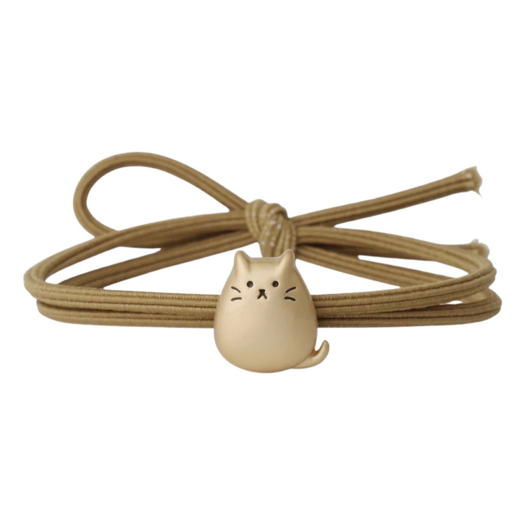 Gold cat-shaped pendant on a coiled gold cord against a white background