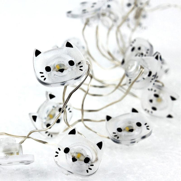 String lights shaped like white cats with black accents on a white background